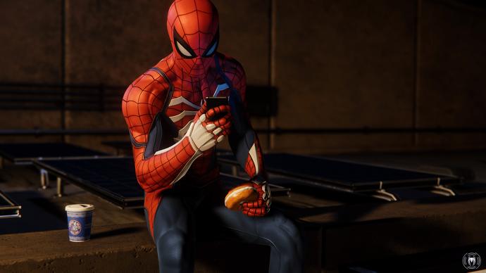 Spiderman sentado en una azotea usando su teléfono mientras bebe café