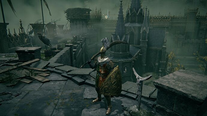 El jugador de Elden Ring se encuentra en una pasarela de piedra junto a una pequeña figura, con vistas a los patios interiores de un castillo